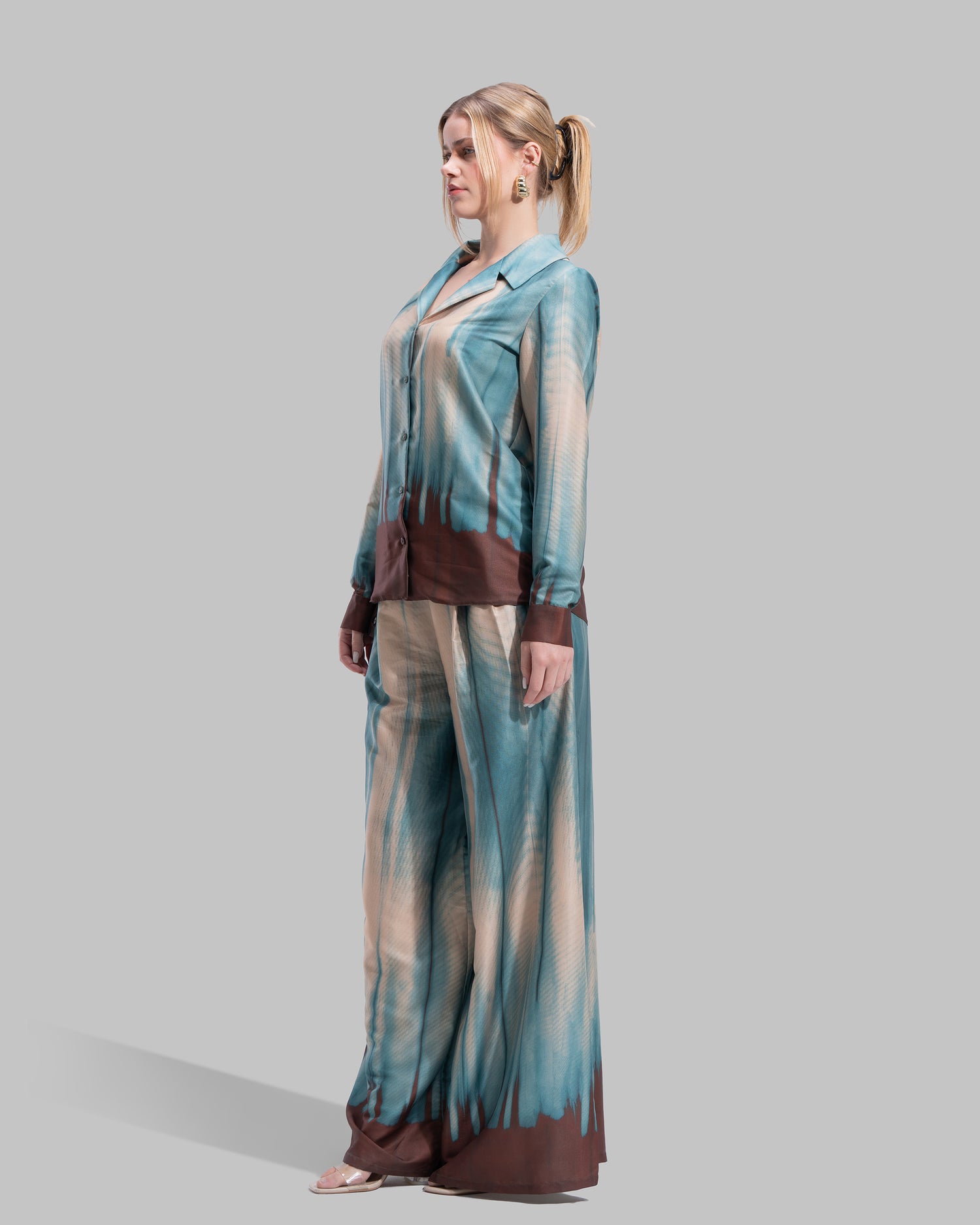 A long-sleeved button-down shirt featuring a teal and cream gradient print with a dark brown hem.