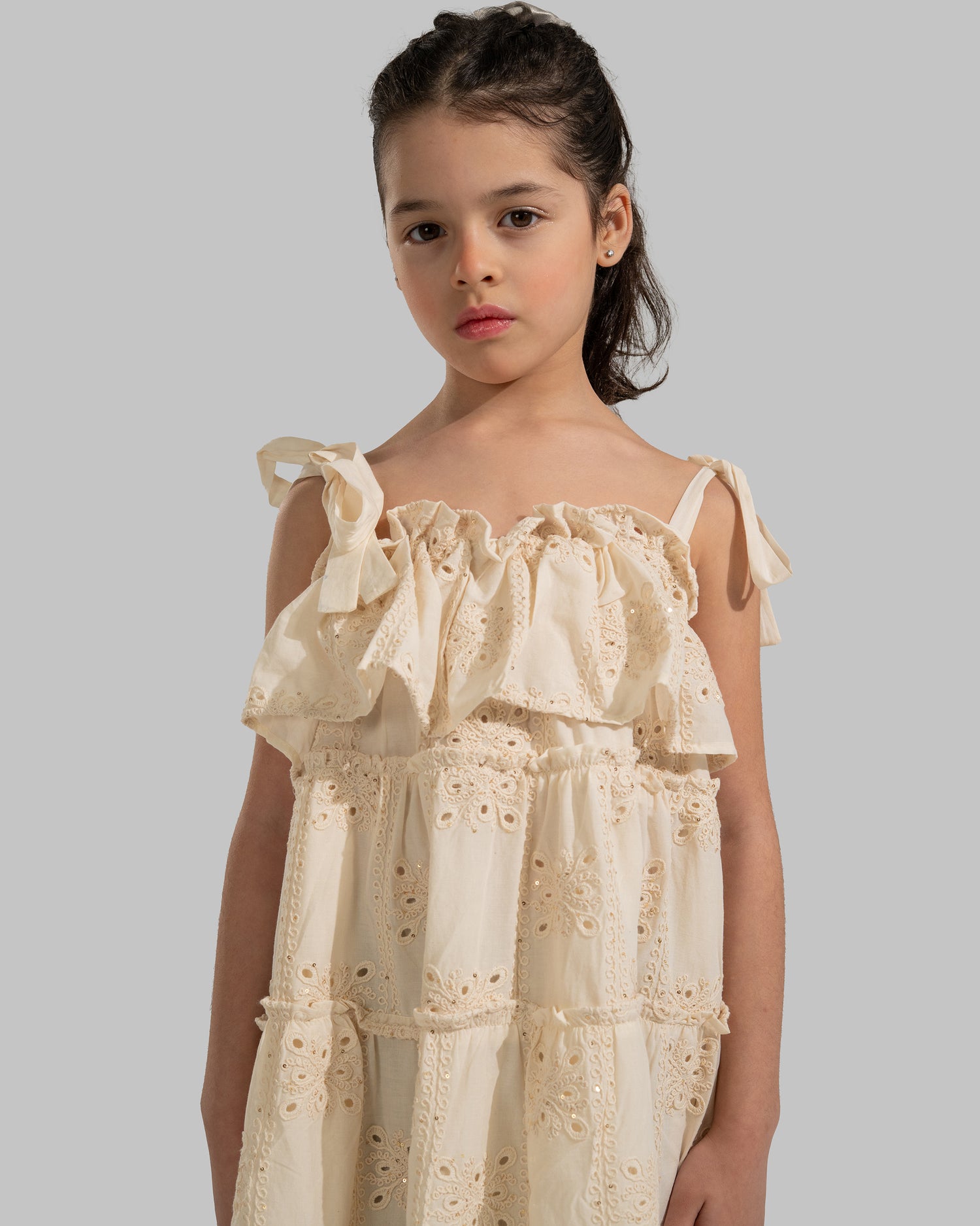 Tiered dress with perforated embroidery, ruffle trim, and tie-up shoulder straps.