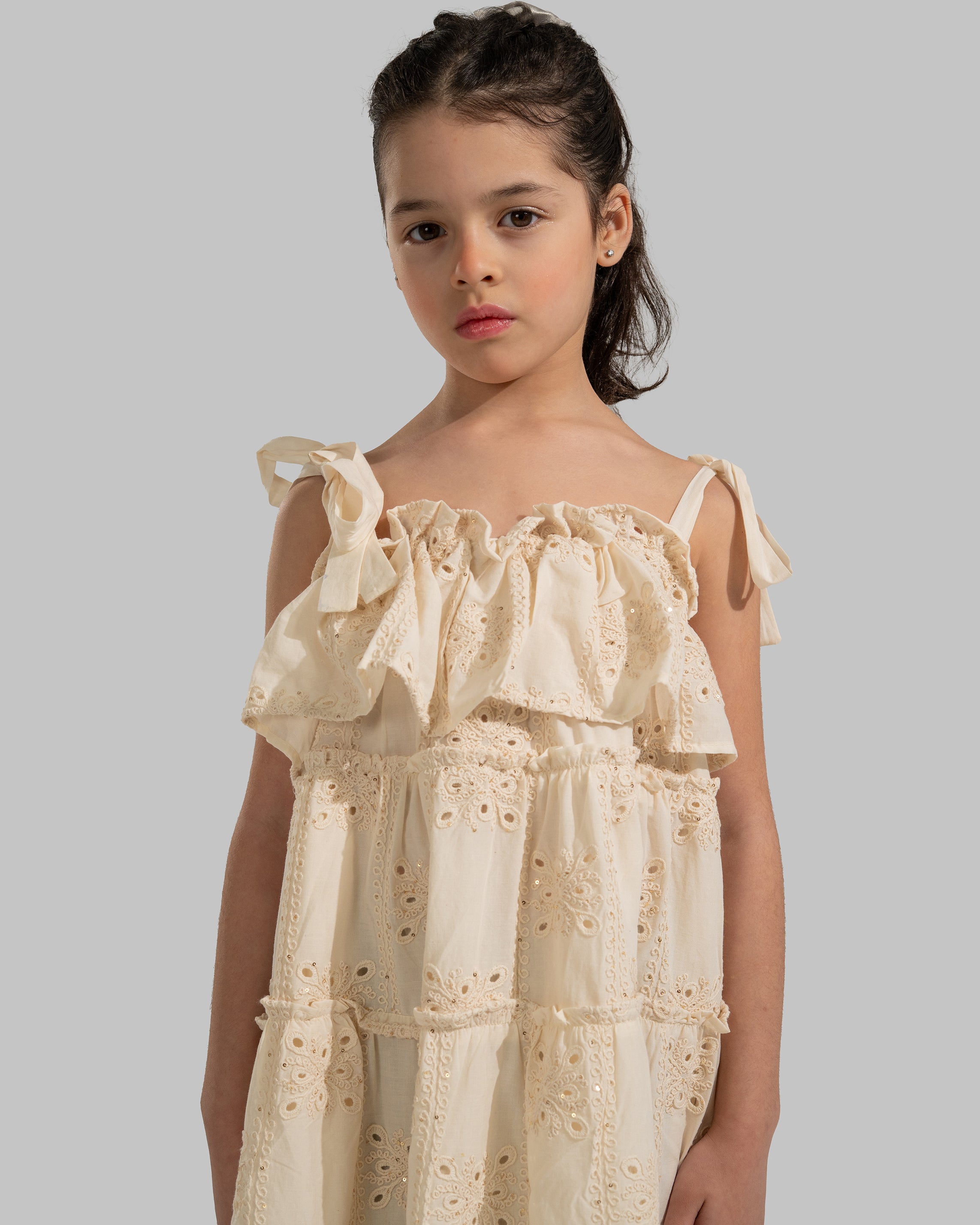 Tiered dress with perforated embroidery, ruffle trim, and tie-up shoulder straps.